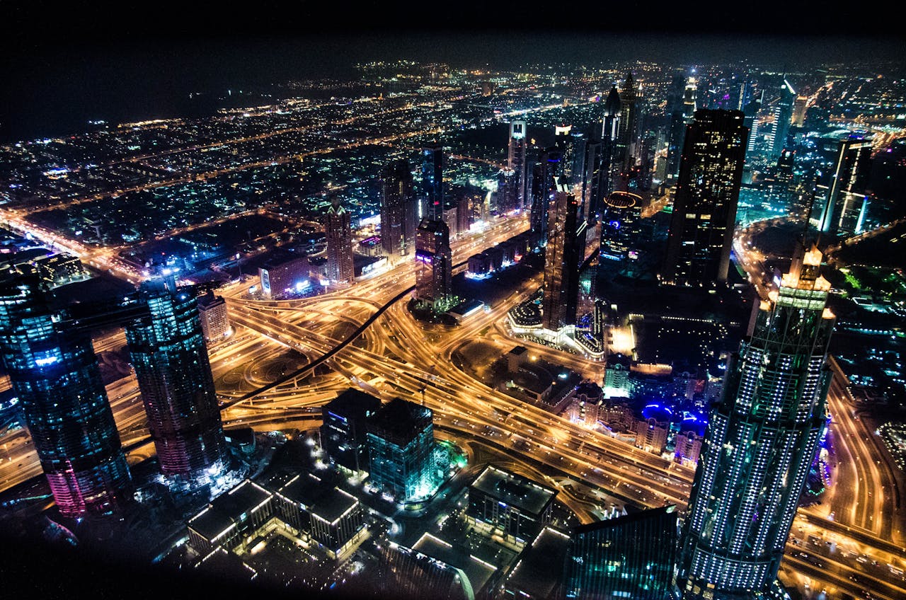 A stunning aerial view of Dubai's illuminated skyline at night, showcasing its modern architecture and busy roads.
